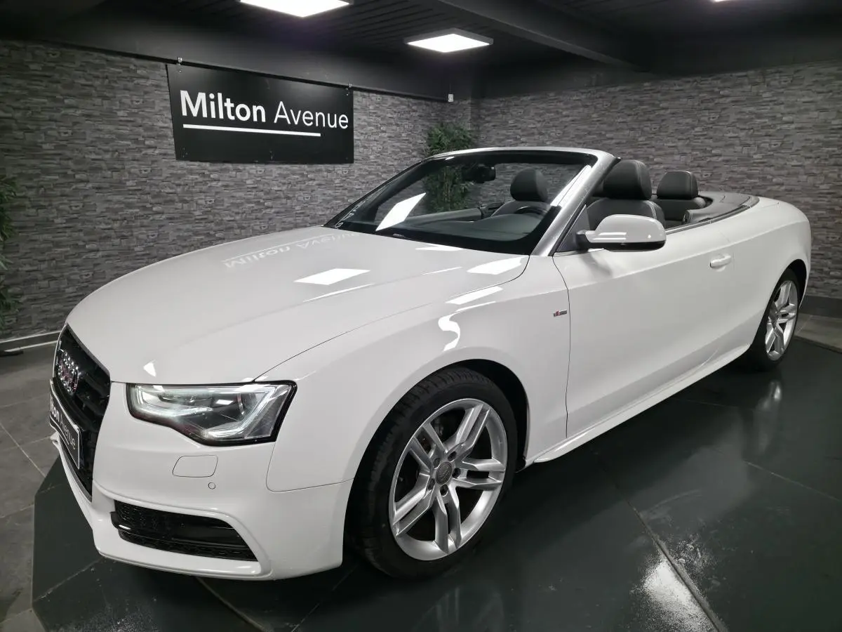 Audi A5 Cabriolet blanc vue 3/4 avant droit, capote ouverte et jantes aluminium sport 5 branches doubles.