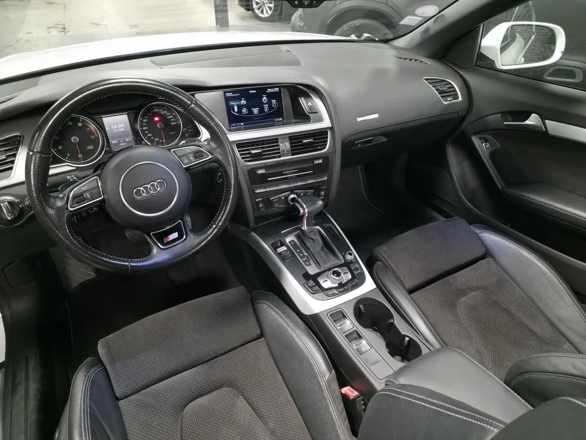 Intérieur noir de l'Audi A5 Cabriolet 2014, vue de face sur le tableau de bord et le volant multifonction S Line.