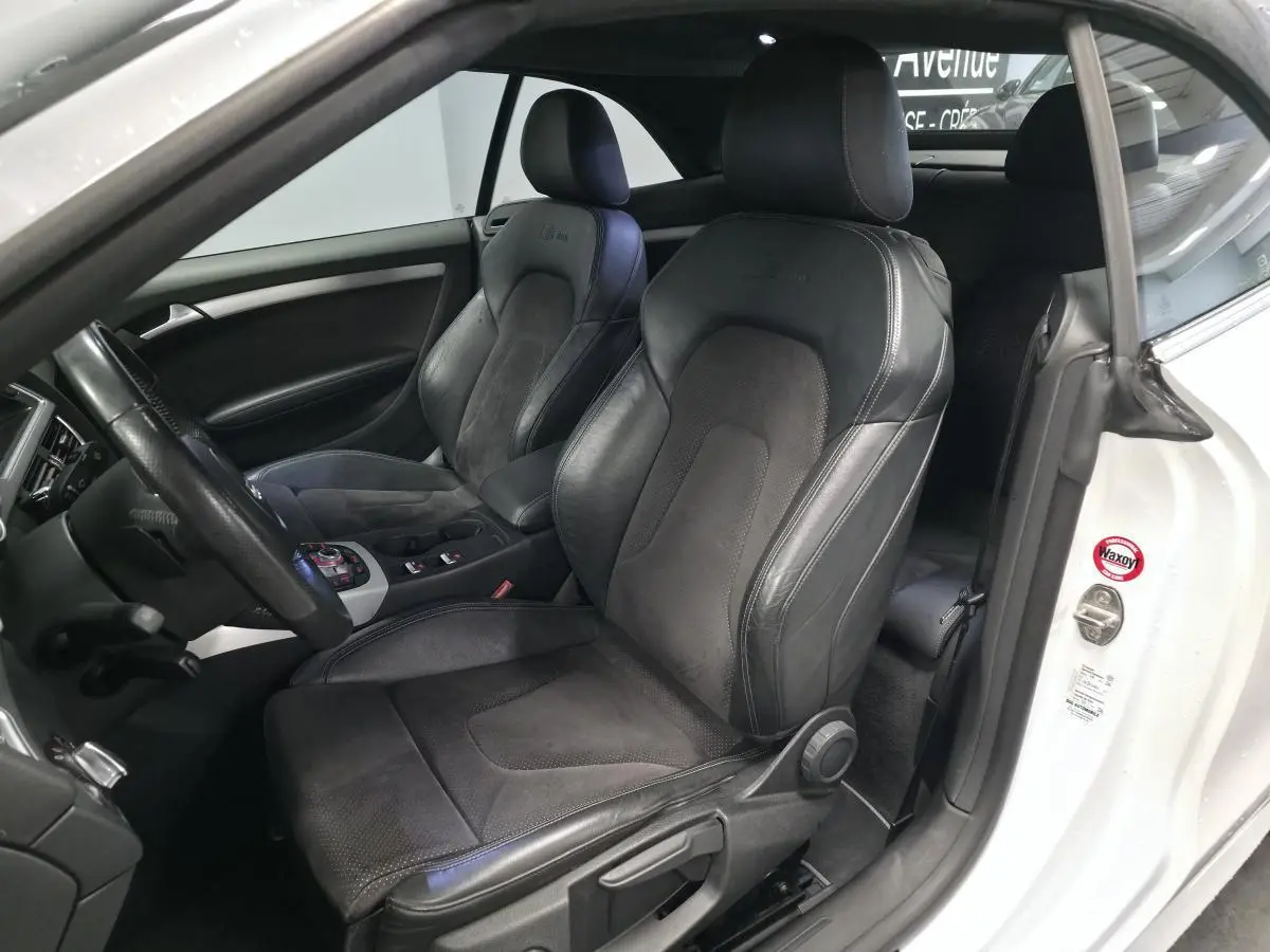 Vue intérieure côté conducteur de l'Audi A5 Cabriolet blanc avec sièges sport S line en cuir noir et alcantara.