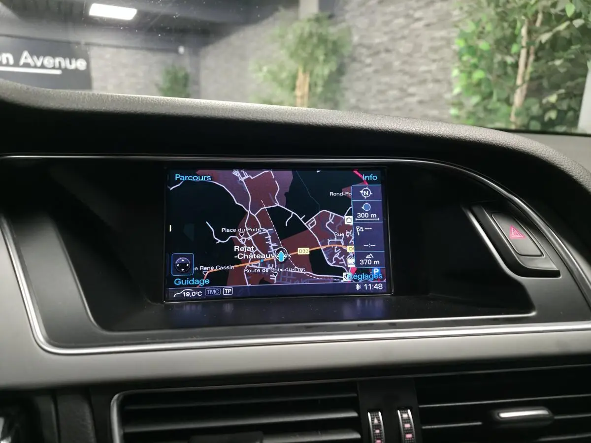Écran de navigation GPS allumé sur le tableau de bord d'un Audi A5 Cabriolet blanc, vue intérieure frontale.