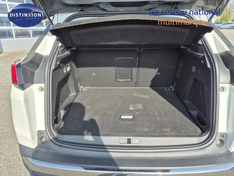 Coffre ouvert vu de l'arrière d'un Peugeot 3008 blanc nacré, montrant l'espace de chargement et la trappe à skis.