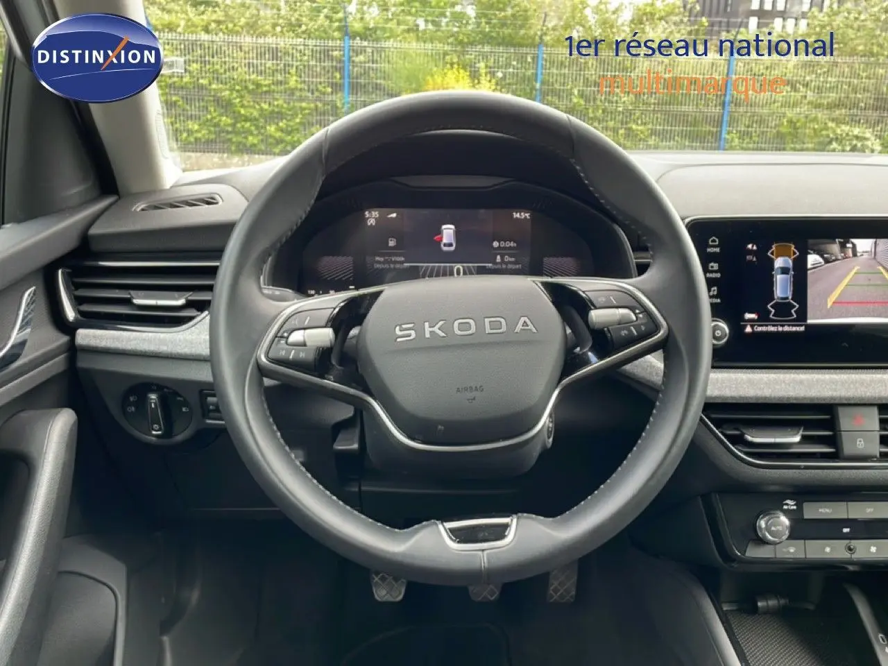 Vue intérieure centrée sur le volant SKODA avec tableau de bord numérique et écran multimédia affichant la caméra 360°