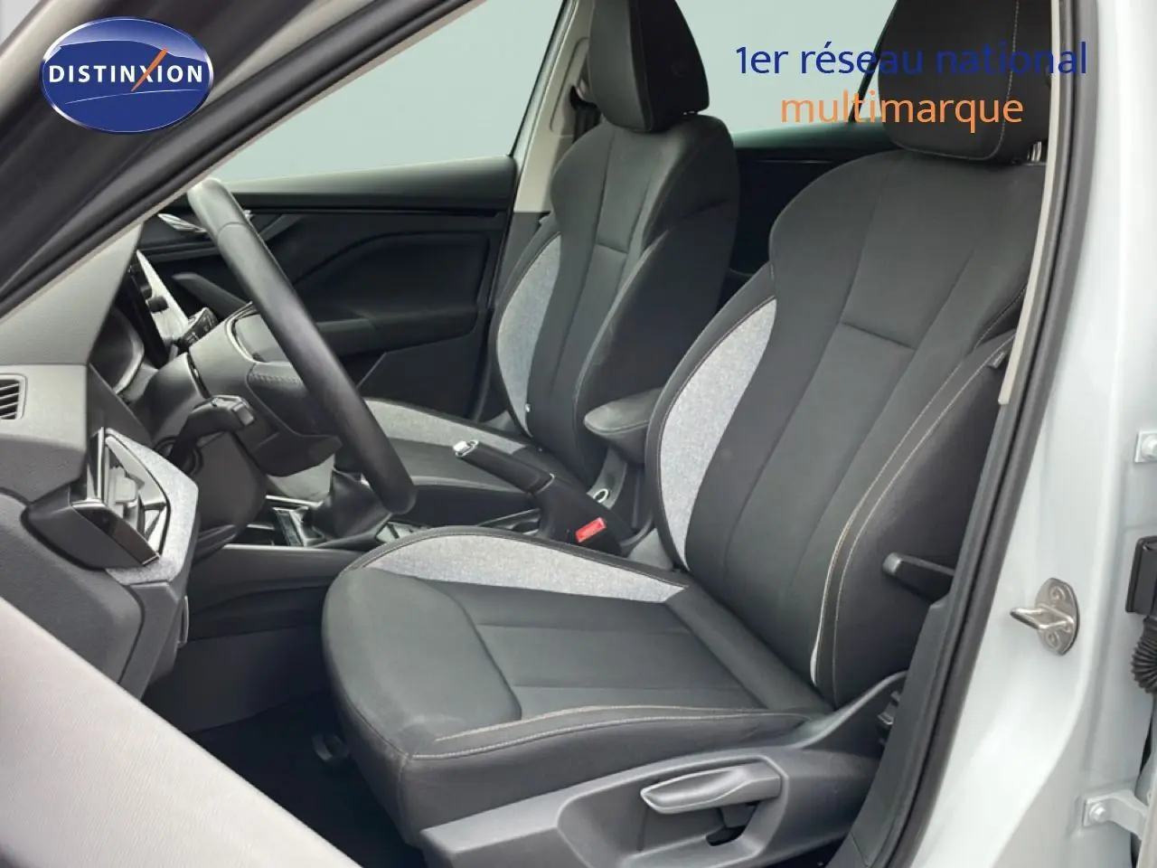 Vue intérieure côté conducteur de la Skoda Scala blanc glacier, sièges tissu gris et noir avec volant multifonction.
