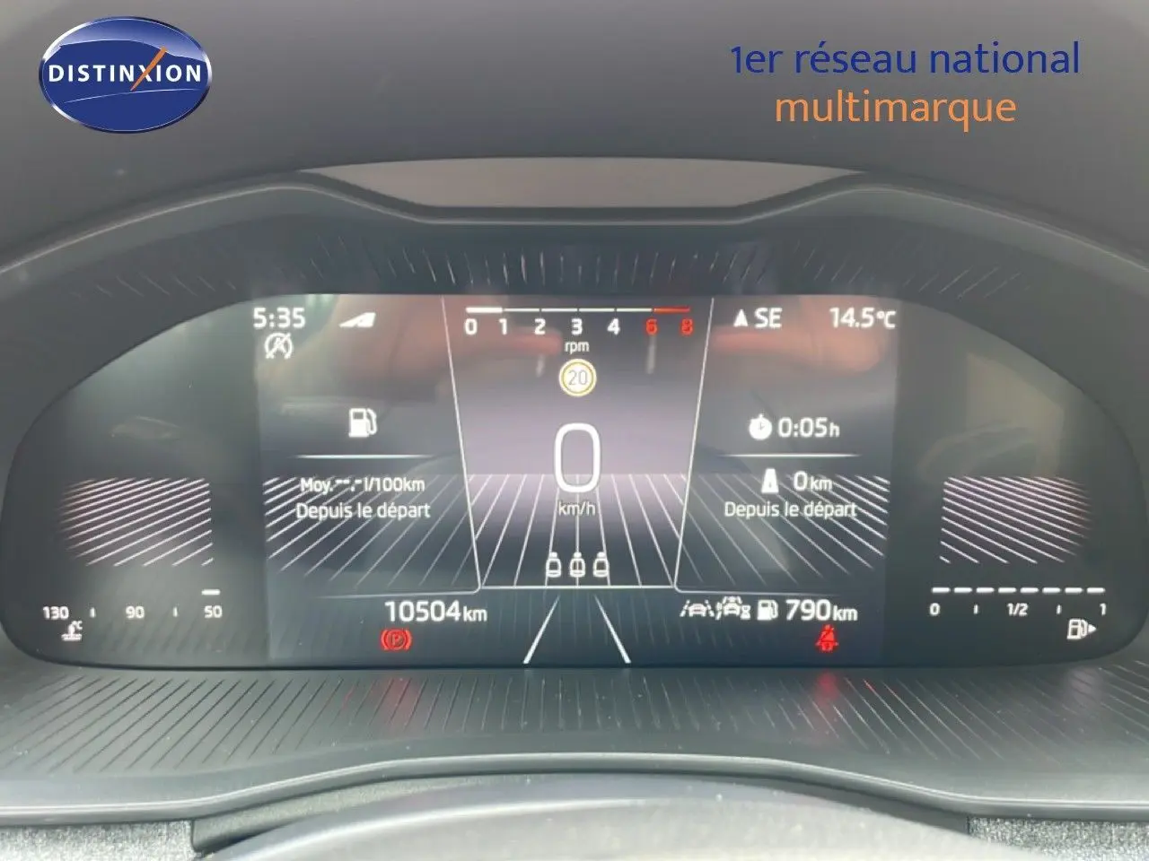 Vue rapprochée du tableau de bord numérique de la Skoda Scala blanc glacier, affichant la vitesse à 0 km/h et 10504 km au compteur.