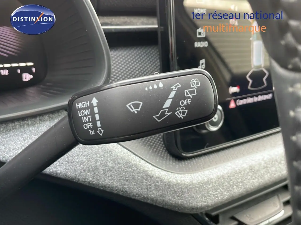 Gros plan sur le commodo d’essuie-glace dans l’habitacle gris noir d’une Skoda Scala blanc glacier, année 2025.
