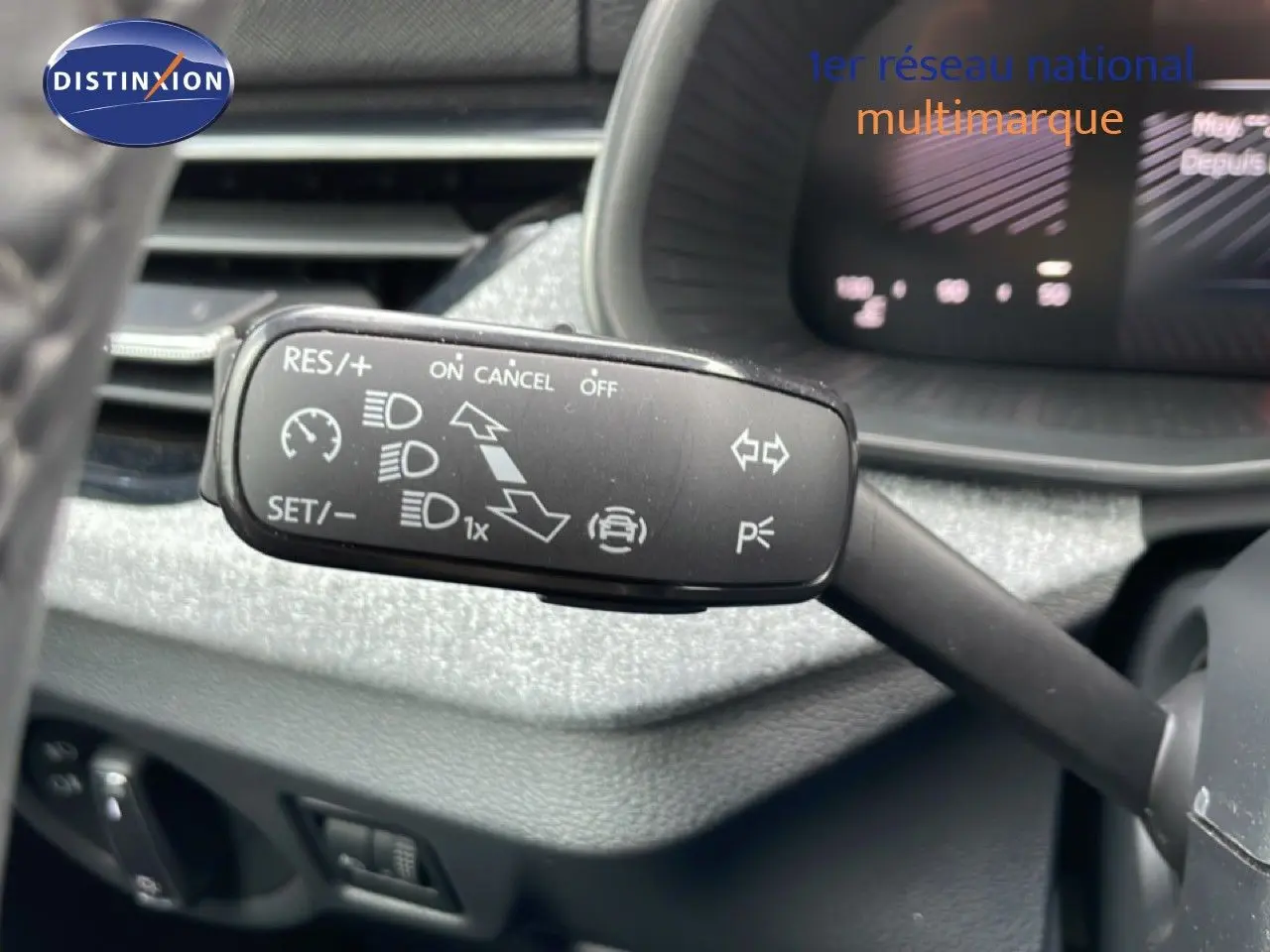 Gros plan sur la commande de régulateur de vitesse au volant d’une Skoda Scala blanc glacier, tableau de bord en arrière-plan flou.