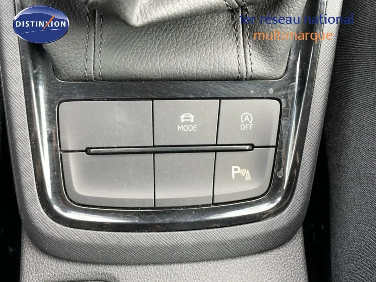 Gros plan sur les boutons de commande du mode de conduite et de l'aide au stationnement dans une Skoda Scala blanche.