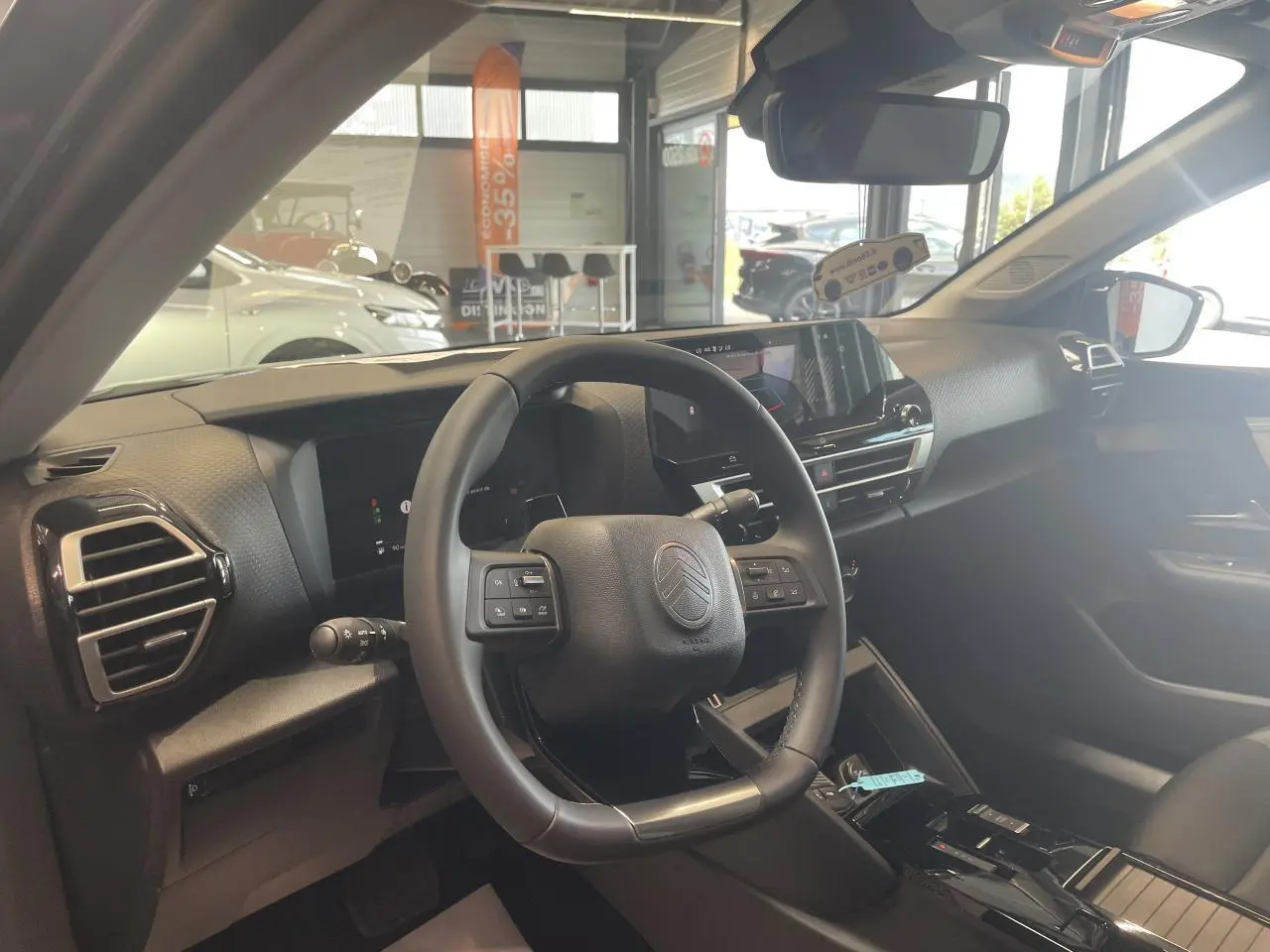 Vue intérieure côté conducteur de la Citroën C4 2026, volant cuir multifonctions et tableau de bord numérique.