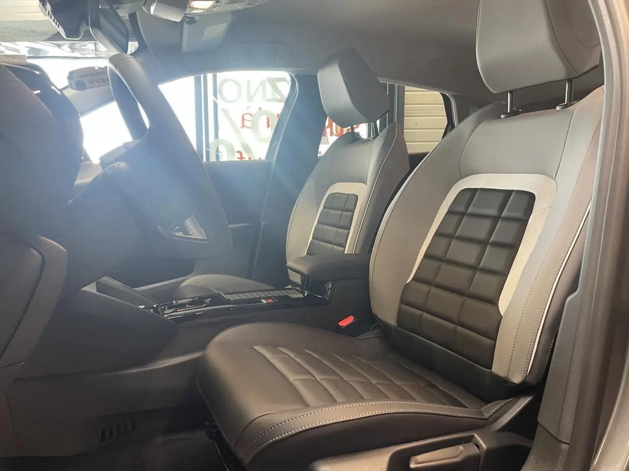 Vue intérieure côté conducteur de la Citroën C4 2026 avec sièges bi-ton gris et noir et accoudoir central.