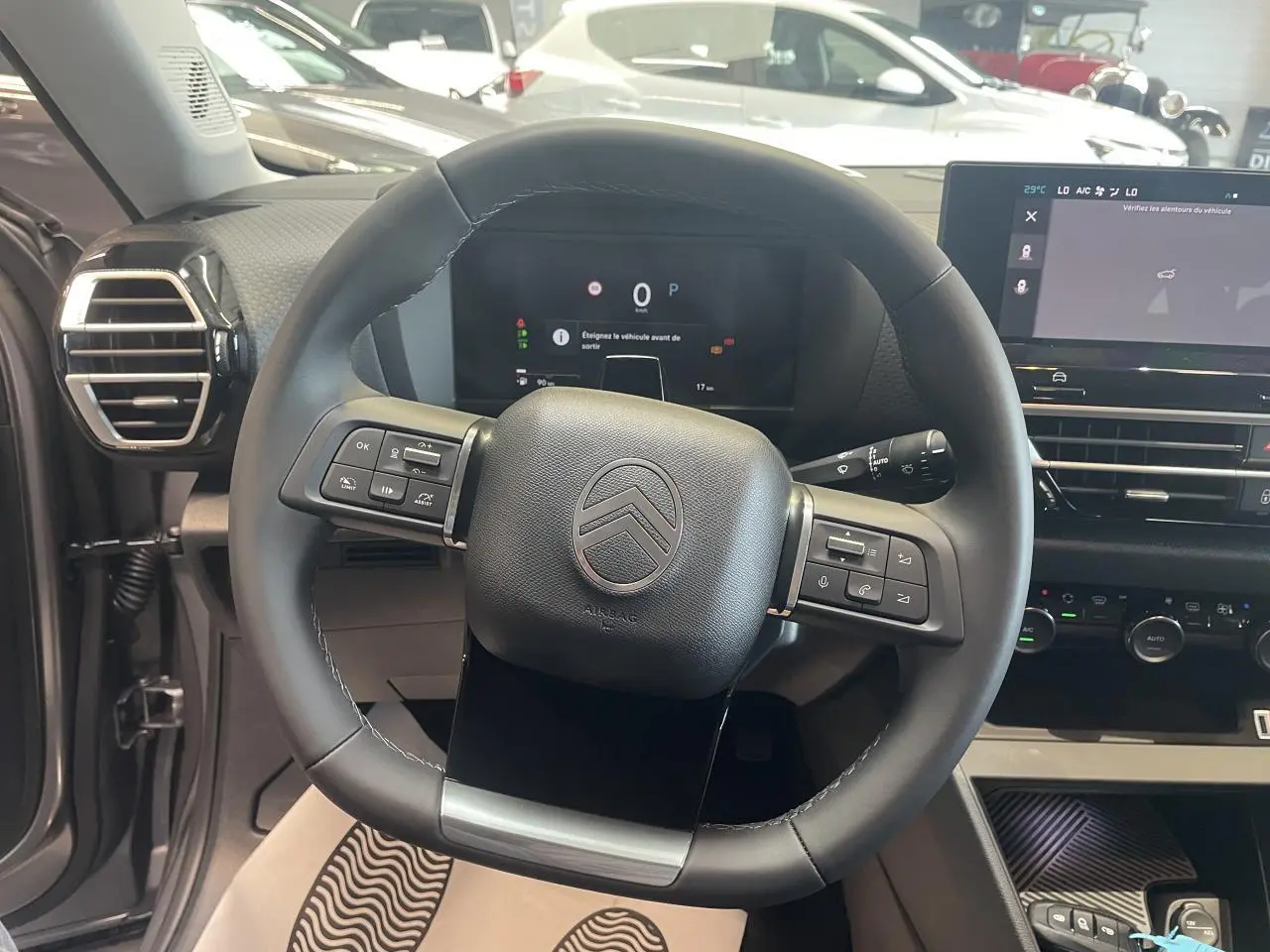 Vue intérieure centrée sur le volant cuir noir de la Citroën C4 avec tableau de bord digital et écran tactile.
