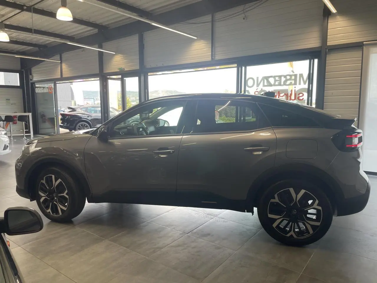 Vue latérale droite d'une Citroën C4 gris métallisé avec toit bi-ton noir Perla Nera en showroom.