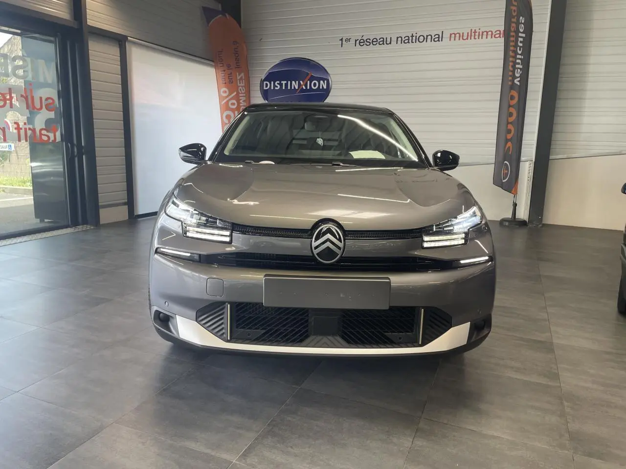 Vue frontale d'une Citroën C4 gris métallisé avec toit noir Perla Nera, dans un showroom intérieur.