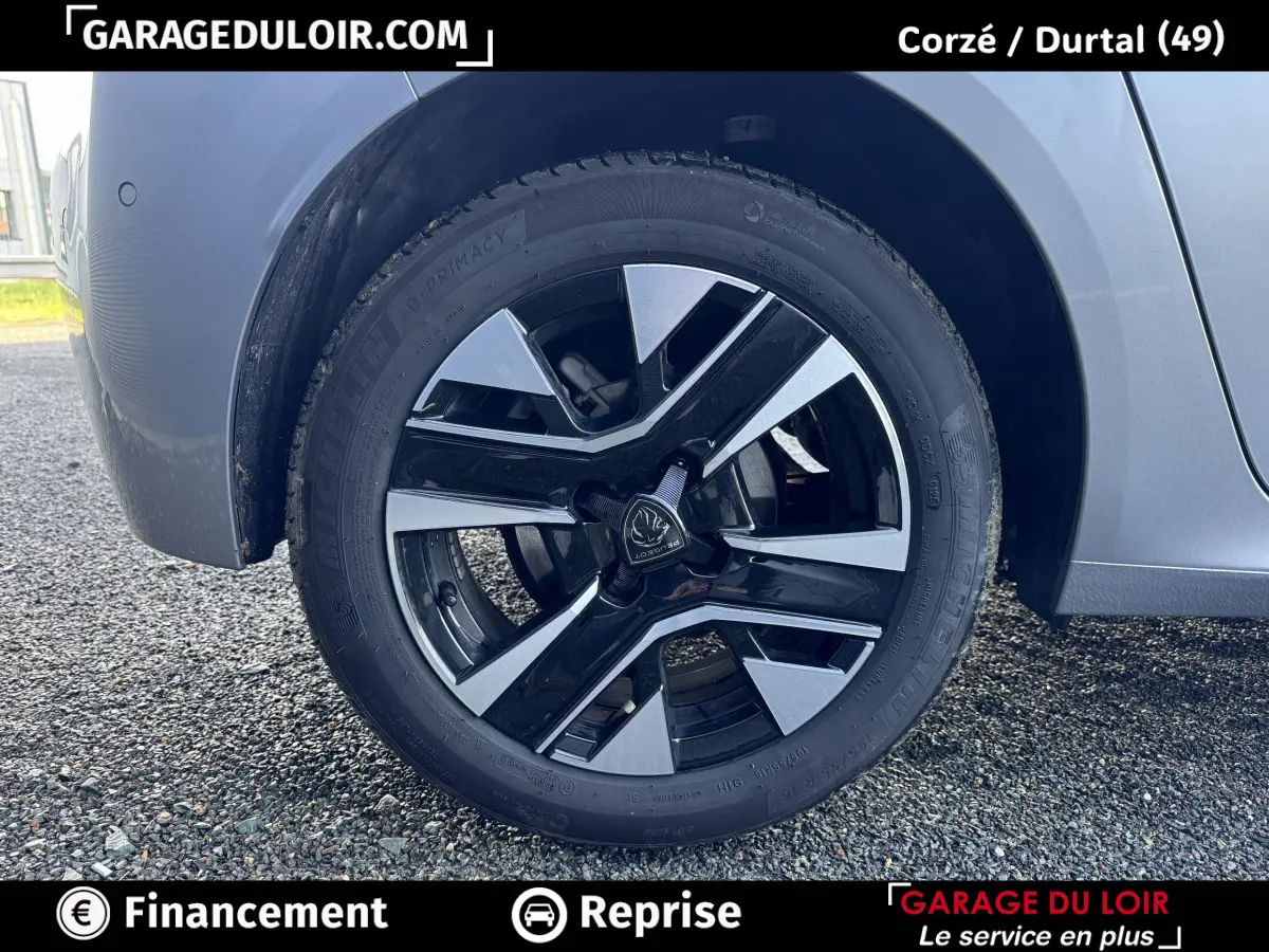 Gros plan sur la roue avant droite gris clair de la Peugeot 208 Hybrid 110 e-DCS6 Allure avec jante noire et argent.