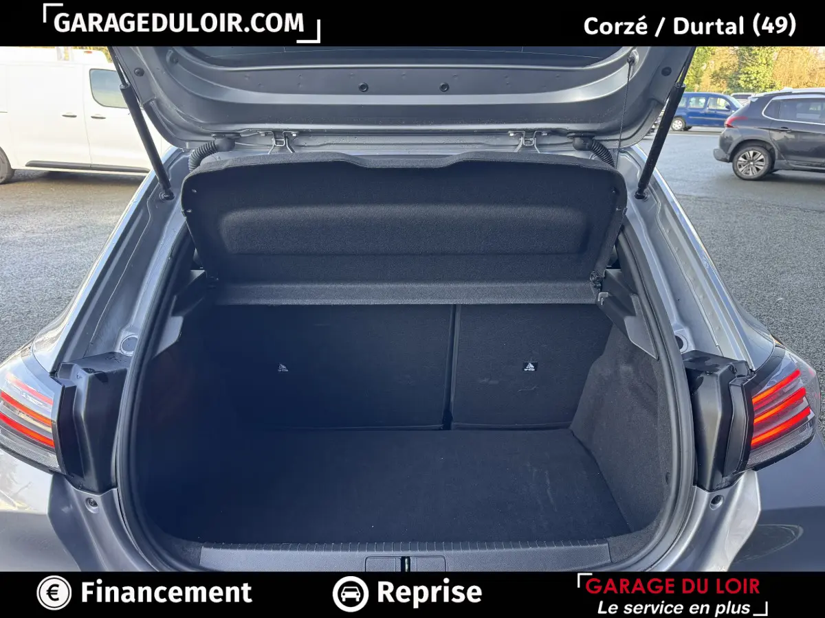 Coffre ouvert vu de l'arrière d'une Peugeot 208 Hybrid 110 gris clair, avec feux arrière LED allumés.