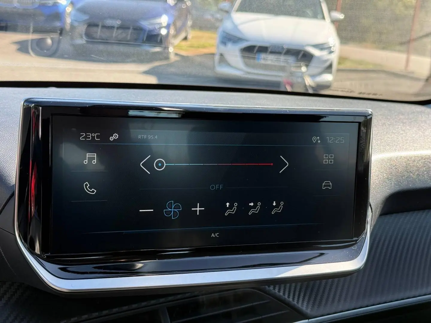 Vue avant du tableau de bord de la Peugeot 208 gris Artense avec écran tactile multifonction allumé.