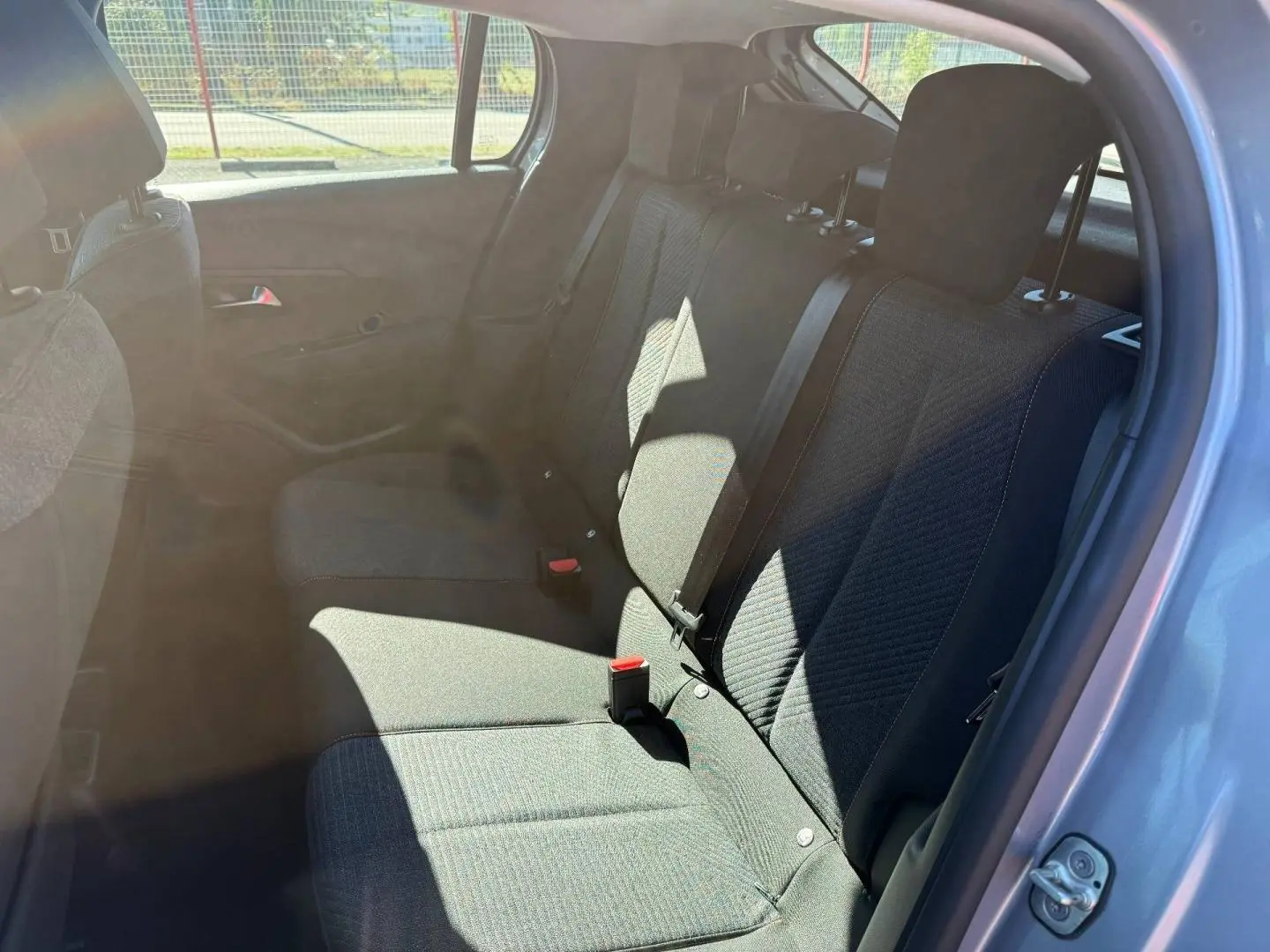 Vue intérieure côté gauche montrant la banquette arrière en tissu gris avec ceintures de sécurité sur une Peugeot 208 2025.