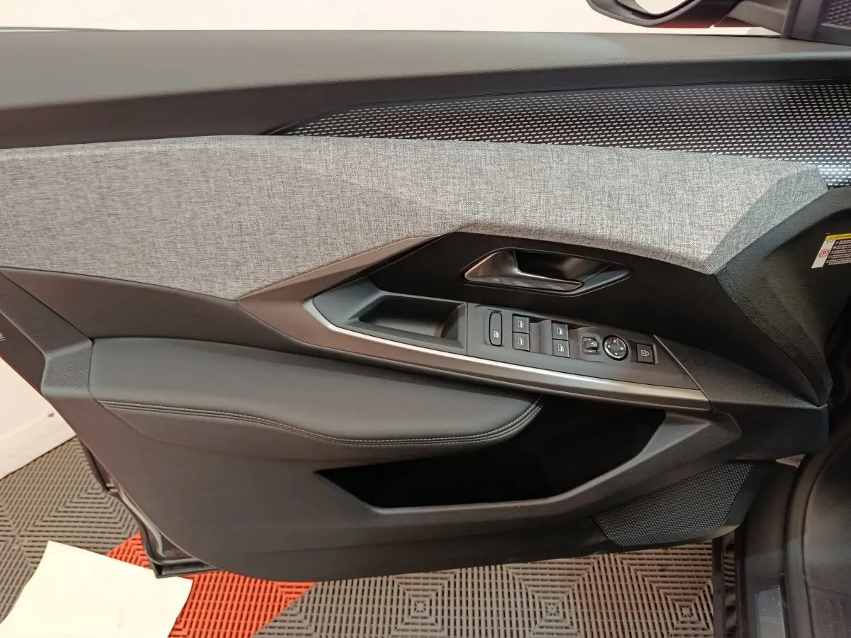 Gros plan sur la porte côté gauche du Peugeot 3008 noir 2025, montrant les commandes de vitres et le revêtement bicolore gris et noir.