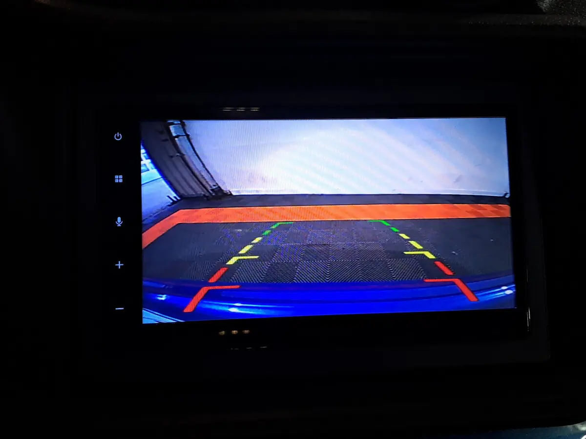 Vue caméra de recul montrant le pare-chocs bleu d'une Aixam Ambition 0.5 City GTO 2025 avec repères de stationnement colorés.