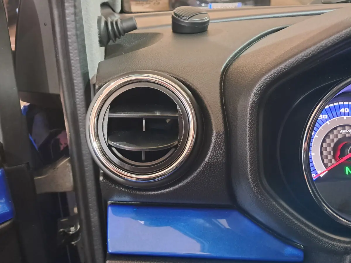 Détail de la sortie d'air ronde chromée côté conducteur sur tableau de bord bleu d'AIXAM AMBITION 2025.