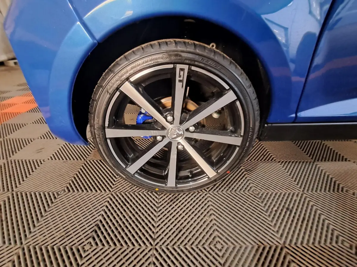 Gros plan sur la roue avant droite d'une Aixam Ambition 2025 bleu avec jante noire et détails gris métallisé