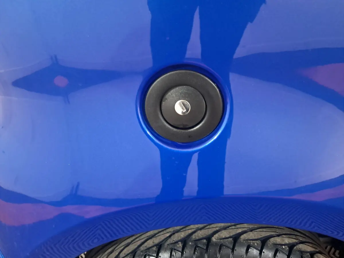 Gros plan sur la trappe de remplissage de carburant noire sur la carrosserie bleue de l'AIXAM AMBITION 2025.