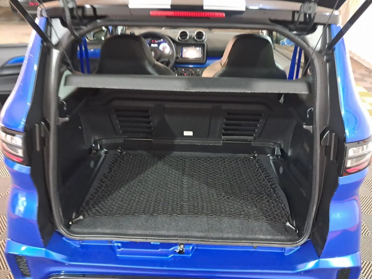 Coffre ouvert d'une Aixam Ambition bleu 2025, vue arrière montrant l'intérieur et les sièges avant.