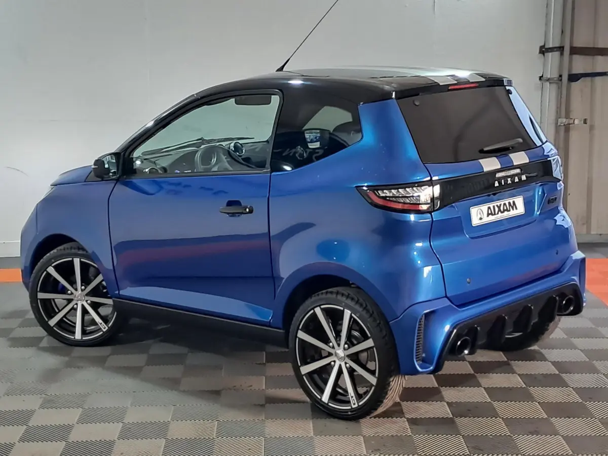 Vue 3/4 arrière droite d'une AIXAM AMBITION 0.5 CITY GTO bleu métallisé avec jantes noires et toit noir.
