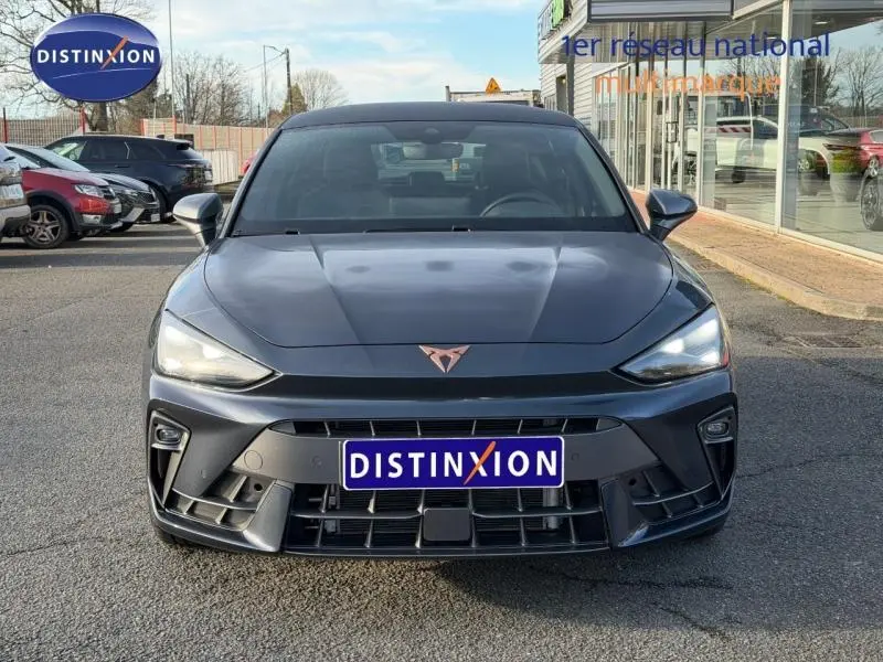 Vue frontale d'une SEAT LEON 1.5 eTSI Hybrid 2025 en gris magnétique métallisé avec logo Cupra distinctif sur le capot.