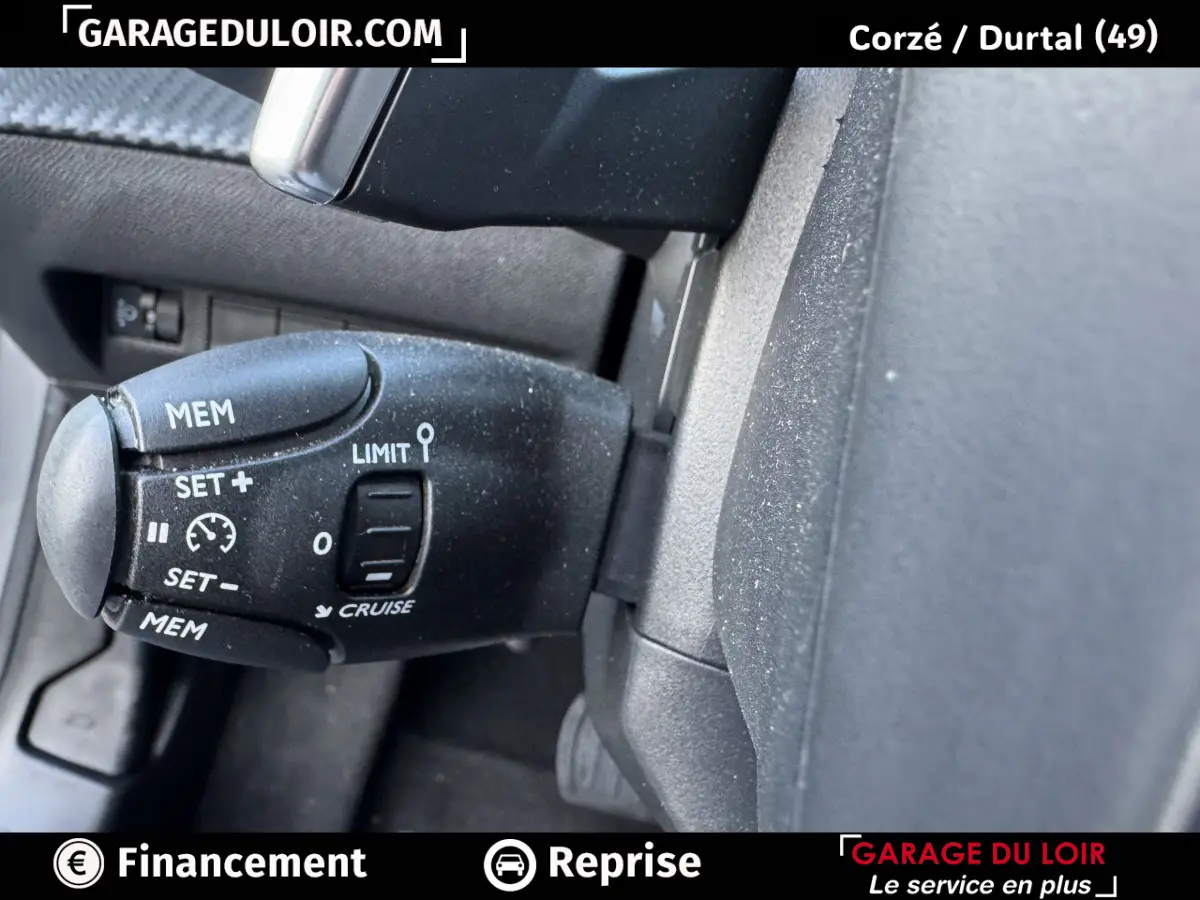 Gros plan sur la commande de régulateur de vitesse noire dans l’habitacle d’une Peugeot 208 gris clair.