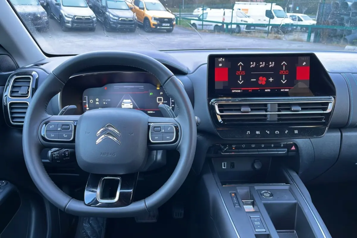 Vue intérieure centrée sur le volant cuir multifonctions et l’écran tactile du tableau de bord du Citroën C5 Aircross Hybrid.
