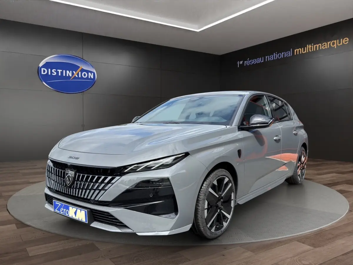 Peugeot 308 gris clair vue 3/4 avant avec calandre distinctive et jantes noires en showroom.