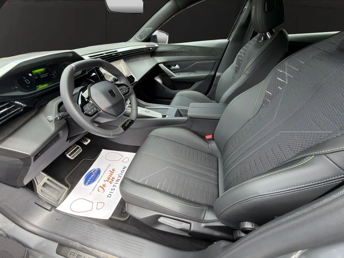 Intérieur avant droit de la Peugeot 308 gris clair 2026, avec sièges tissu et cuir, volant multifonction et tableau de bord numérique.