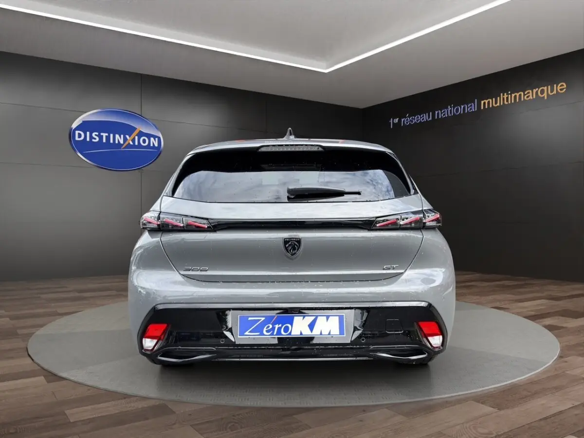 Vue arrière d'une Peugeot 308 GT gris clair avec feux LED et logo lion au centre du hayon.