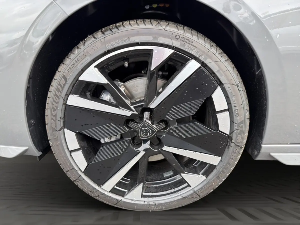 Gros plan sur la roue avant droite gris clair de la Peugeot 308 2026 avec jante noire et argentée au design moderne.