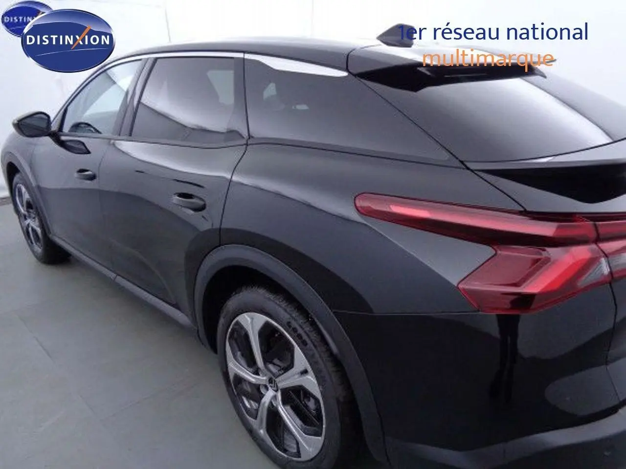 Vue 3/4 arrière droite d'une Citroën C5 X noire métal avec feux arrière étirés et jantes alliage modernes.