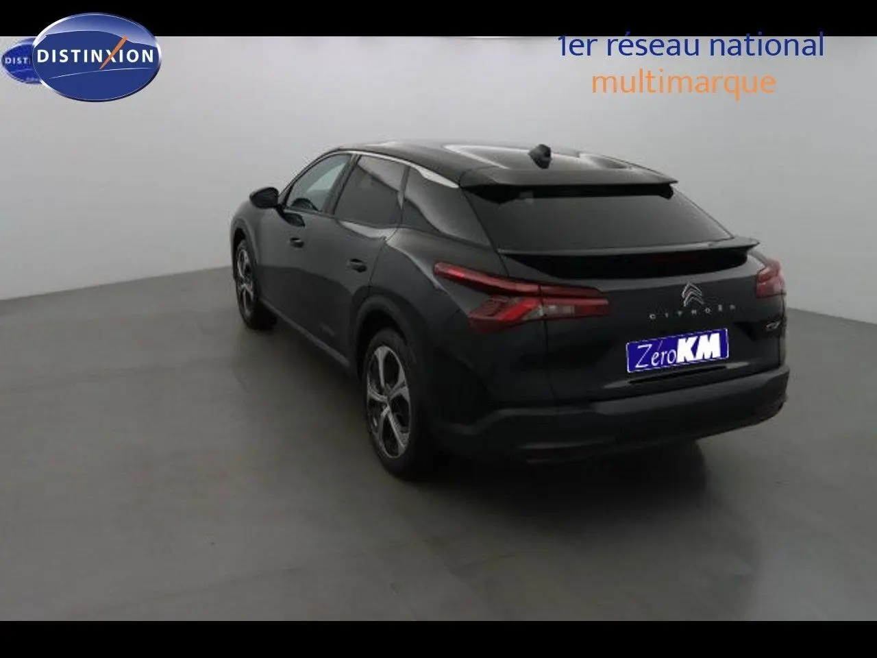 Vue 3/4 arrière droite d'une Citroën C5 X noire métal, avec feux arrière allongés et toit surélevé dans un studio.