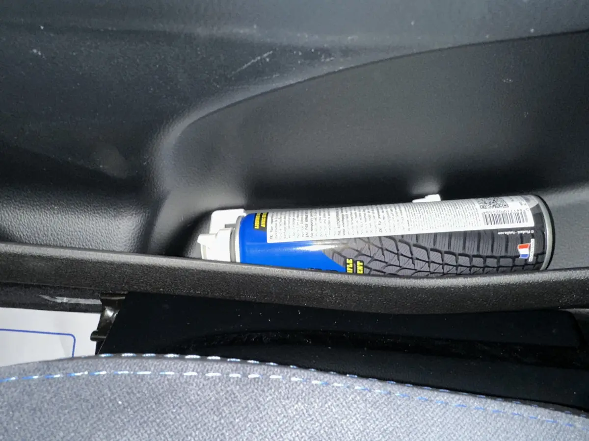 Gros plan sur le rangement intérieur côté conducteur d'une Aixam Ambition rouge 2025 avec un spray bleu posé.