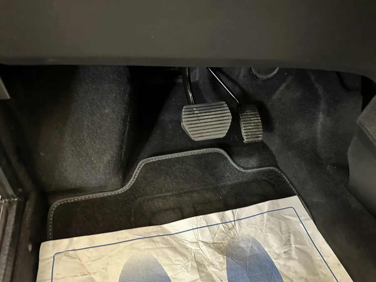 Gros plan sur les pédales et tapis noirs de l'AIXAM AMBITION 0.5 CITY COUPE GTI E5+ 2025, sans vue extérieure du véhicule.