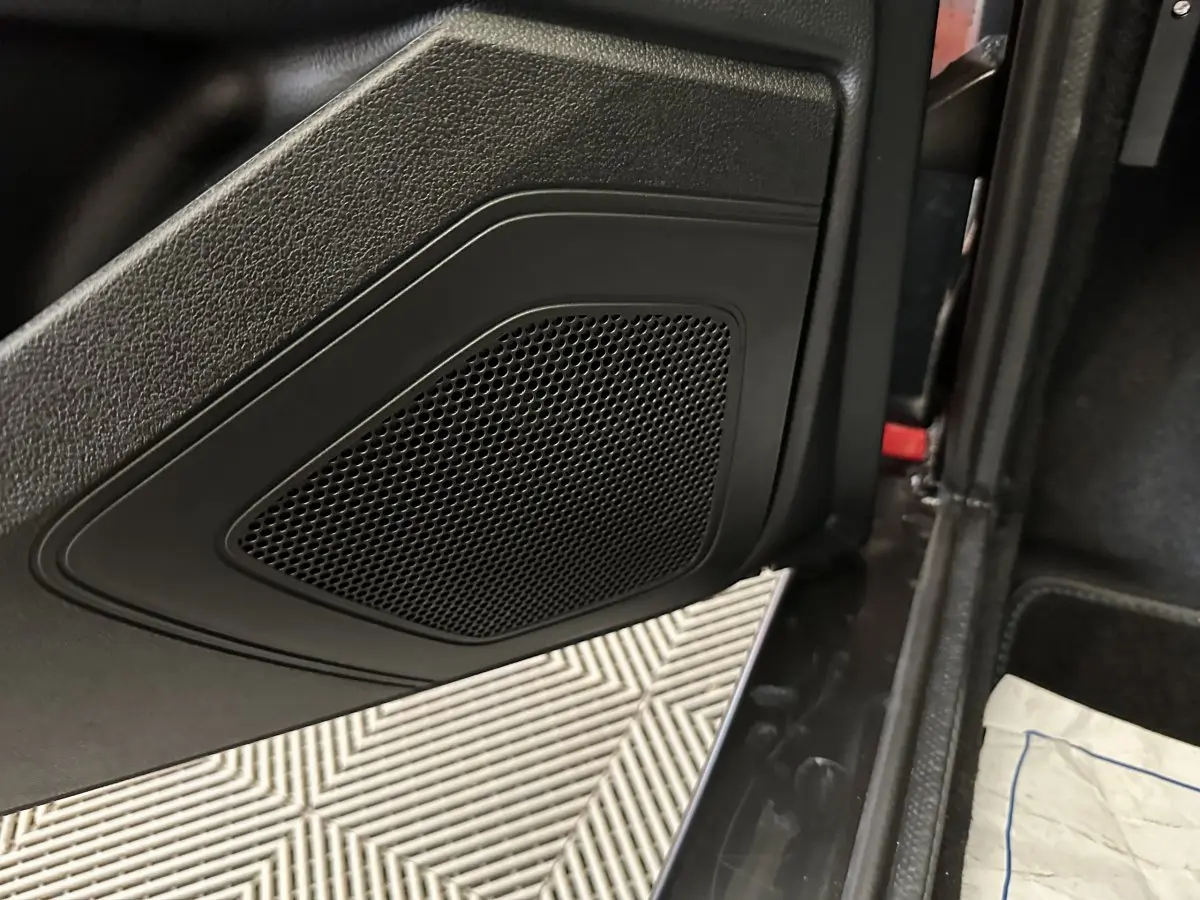 Gros plan sur la porte intérieure noire d'une Aixam Ambition rouge, mettant en valeur le haut-parleur intégré.