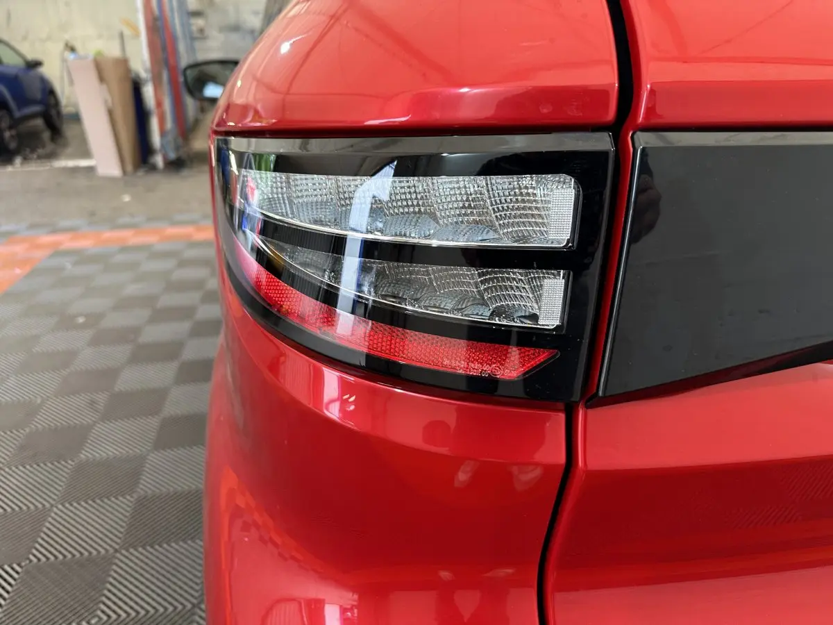 Gros plan sur le feu arrière droit rouge brillant de l'AIXAM AMBITION 2025 avec bande noire distinctive.