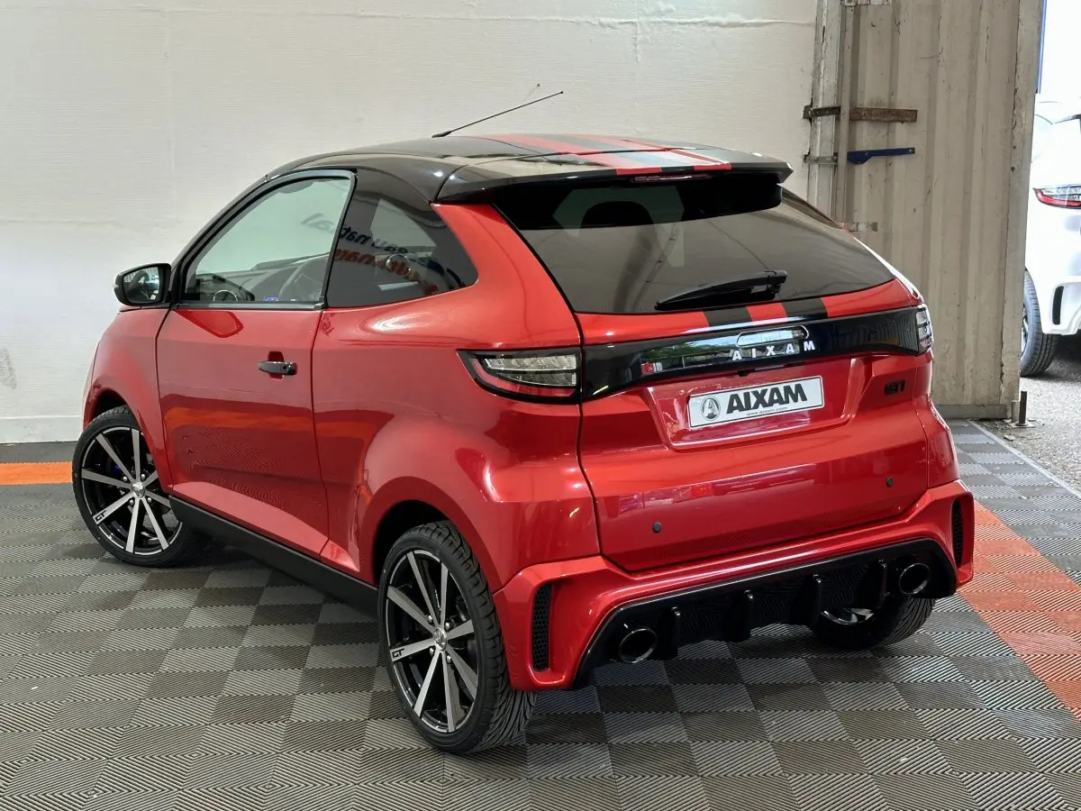 Vue 3/4 arrière droite d'une Aixam Ambition 0.5 City Coupe GTI rouge avec toit noir et jantes sport noires.