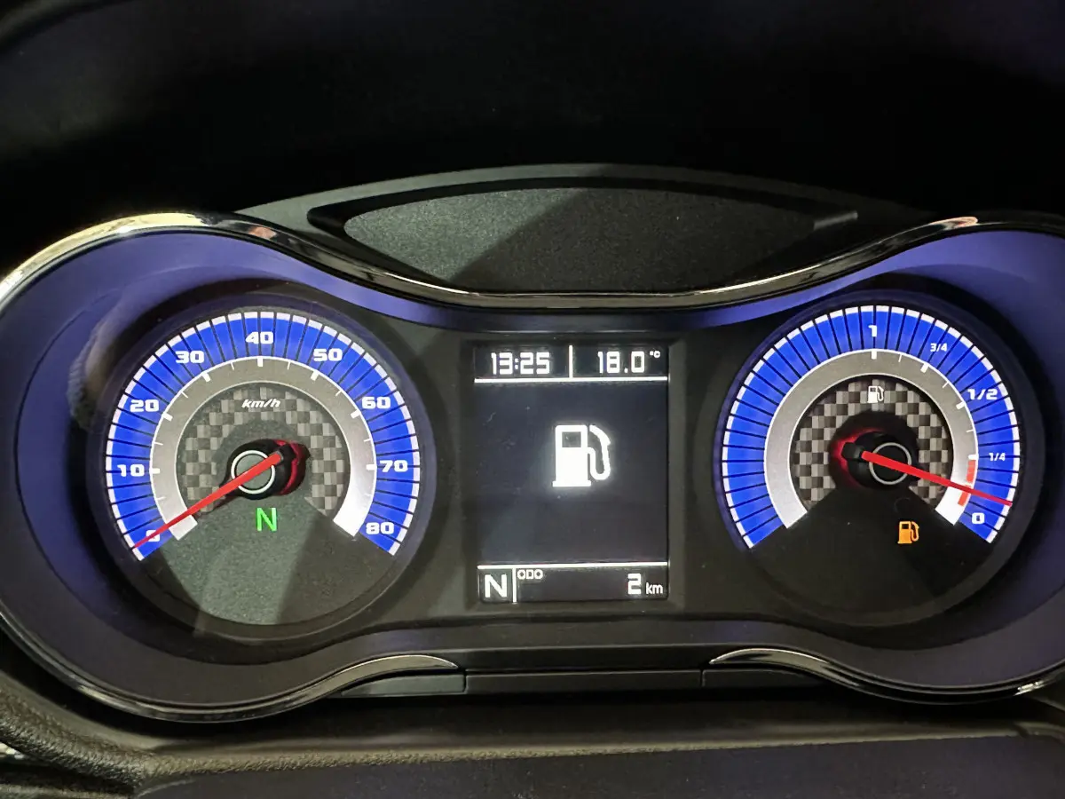 Tableau de bord de l'AIXAM AMBITION rouge 2025 montrant compteur vitesse, jauge carburant et écran digital central.