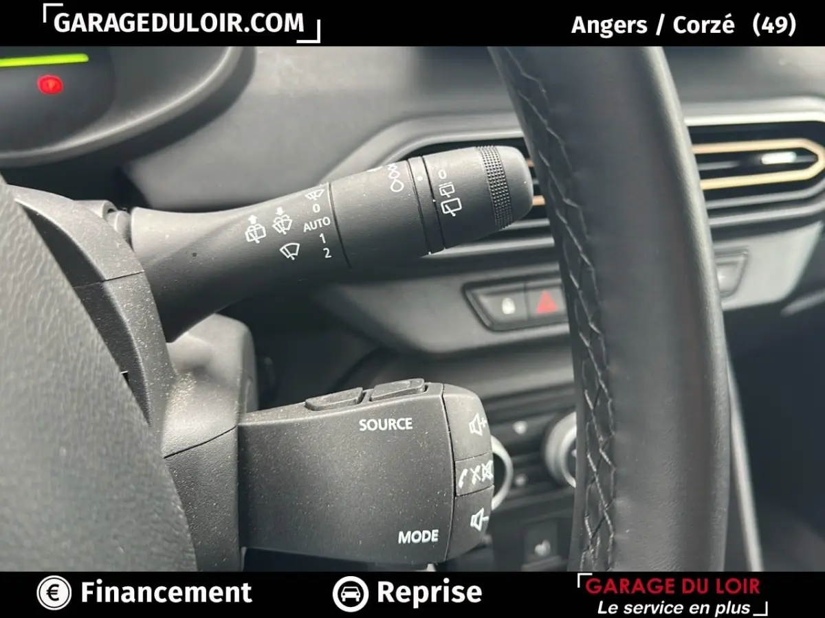 Gros plan sur la commande de clignotants et le volant noir du Dacia Jogger Extreme+ Hybrid 2025, intérieur sombre.