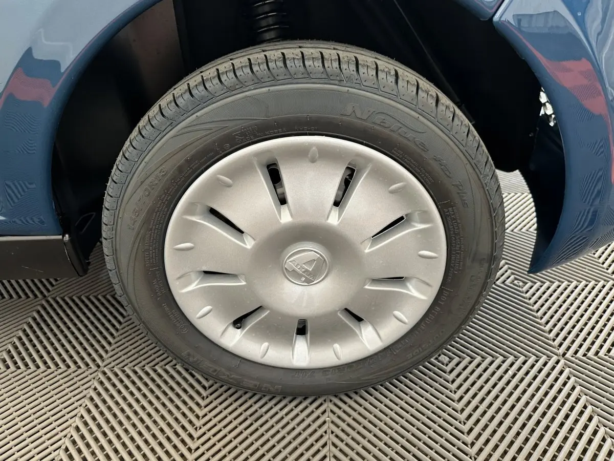 Gros plan sur la roue avant droite de l'AIXAM AMBITION 0.5 CITY PACK bleu 2025 avec jante argentée et logo central.