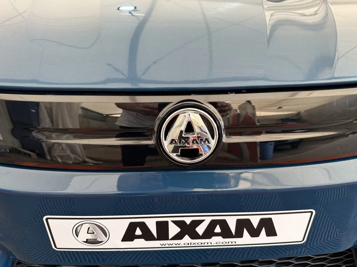 Gros plan sur la calandre avant bleue de l'AIXAM AMBITION 0.5 CITY PACK avec logo central chromé.