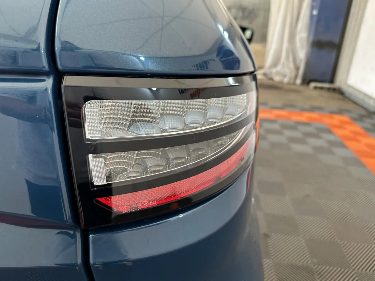 Gros plan sur le feu arrière droit bleu de l'AIXAM AMBITION 0.5 CITY PACK 2025 avec détails lumineux distinctifs.