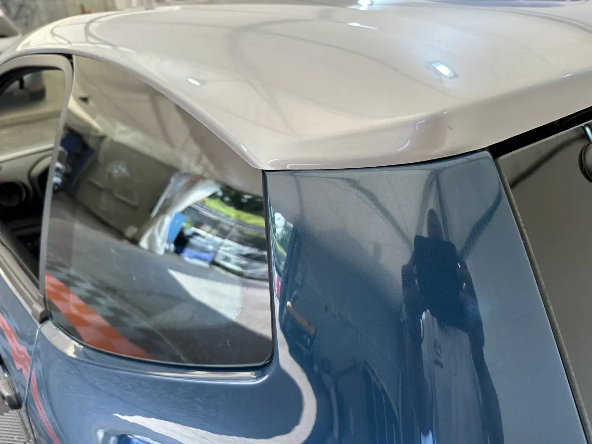 Vue rapprochée arrière gauche de l'AIXAM AMBITION 0.5 CITY PACK bleu avec toit clair et rétroviseur caméra côté conducteur.