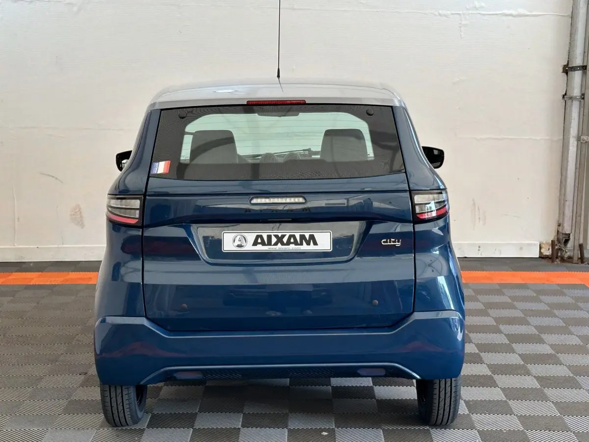 Vue arrière d'une Aixam Ambition 0.5 City Pack bleu 2025 avec rétroviseur caméra côté gauche visible.