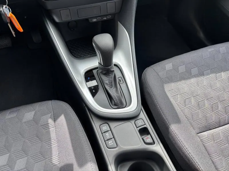 Vue rapprochée de la console centrale de la Toyota Yaris blanche 2025, mettant en valeur le levier de vitesse automatique et les sièges tissu.