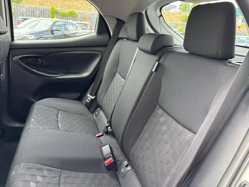 Vue intérieure arrière de la Toyota Yaris 2025 blanche, montrant les sièges arrière en tissu gris avec motifs géométriques.